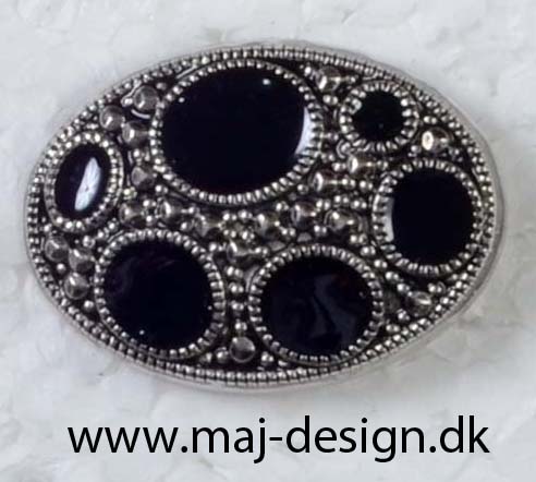 Oval metal knap med sorte sten i sølvfarvet fatning til tøj.